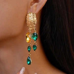 Vintage geometric gold drop earrings with yellow and green gemstones on a model