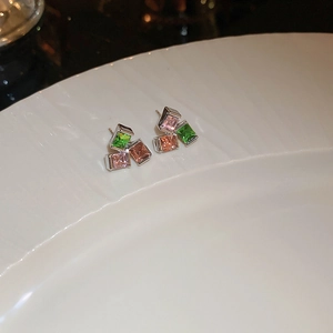 Macro shot of colorful square zircon earrings with pink green and champagne crystals