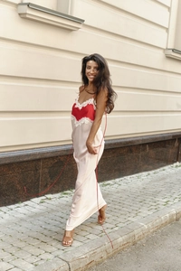Detail of elegant V-neck satin maxi dress with red lace trim and pale pink skirt