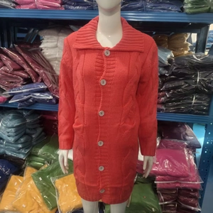 Close-up of coral orange cable knit cardigan with wide lapels and grey buttons