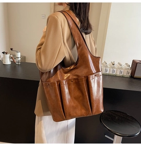 Close-up of vintage brown PU leather tote bag with large pocket worn by a model