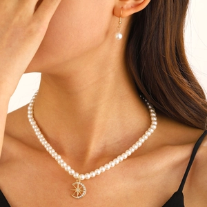 Detail of pearl necklace with gold crescent moon pendant and matching earring set