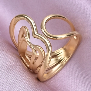 Macro d'une bague dorée en forme de cœur sur un tissu de soie rose satiné