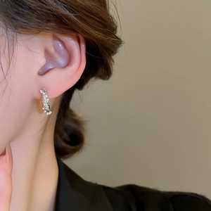 Close-up of elegant silver hoop earrings with white pearls and sparkling zircons on ear