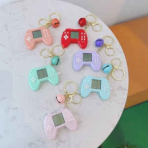 Flat lay of retro mini handheld game console keychains in seven vibrant colors on marble