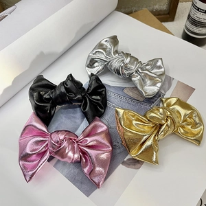 Metallic bow hair clips in silver, black, pink, and gold on a magazine page