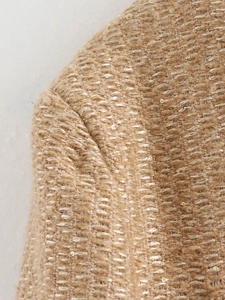 Detail of tweed fabric with gold sequins and fine stitching on the shoulder seam