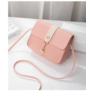 Detail of pink PU leather crossbody bag with beige strap and pearl tassel charm