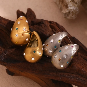 Détail macro de boucles d'oreilles goutte avec strass colorés sur socle en bois
