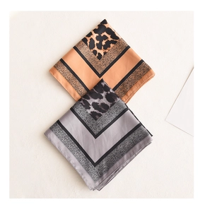 Close-up of leopard print satin scarves in orange and grey with geometric V-patterns