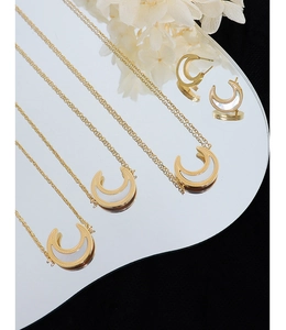 Detail of crescent moon necklace and earrings with white shell inlays on mirrored surface