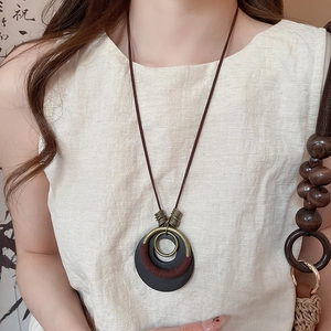 Detail of vintage wooden pendant necklace with bronze ring on linen clothing