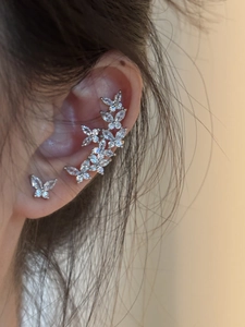 Detail view of silver butterfly stud earrings and ear cuffs with white zirconia stones
