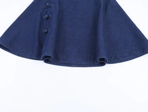 Close-up of traditional knot buttons on dark blue denim poncho top with textured fabric