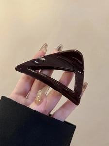 Macro shot of dark brown polished triangular hair claw clip with glossy resin finish