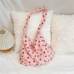 Sac fourre-tout en velours rose avec imprimé fraises sur une surface en peluche blanche