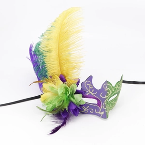 Macro detail of carnival mask with purple and green feathers, gold glitter and silk flower