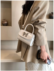 Dettaglio mini borsa in pelle verniciata bianca con decorazione a fiocco in argento