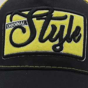 Macro detail of original style embroidery on black mesh trucker cap with yellow patch