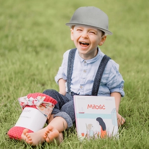Close-up of a child wearing a grey sun hat with a red knitted blanket in an outdoor park