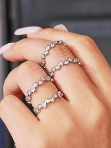 Detail of four stackable silver rings with white round-cut zircons on a model's finger