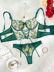 Flat lay of lace lingerie set with floral embroidery and bow details on white fabric