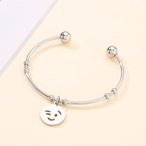 Close-up of silver titanium steel open bangle with a cute winking smiley face charm