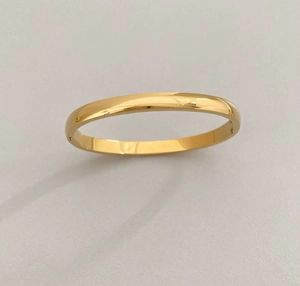 Close-up of a minimalist gold-plated stainless steel bangle with polished mirror finish