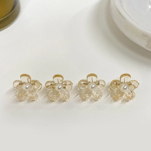 Close-up of four amber resin flower hair clips with pearls on a white background