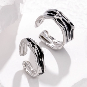 Detail of silver stainless steel rings with black enamel inlay on white textured stone