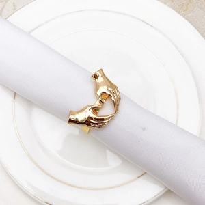 Macro view of golden metal heart-shaped napkin ring on a white napkin over a plate