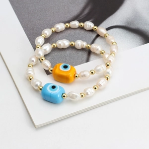 Detail of freshwater pearl bracelets with blue and yellow evil eye charms on a magazine