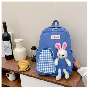 Detailed shot of a blue cartoon backpack with a white plush rabbit and checkered pocket