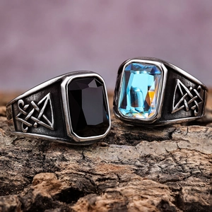 Detailed macro view of vintage men's rings with black and blue gems on bark texture