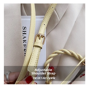 Detail of adjustable strap with gold buckle and twisted handle on cherry print bag