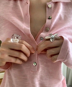 Close-up of a silver flower ring with white pearl and a clear resin square ring