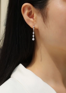Macro shot of 925 silver drop earrings with three graduated moissanite stones on a model