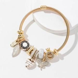 Golden DIY charm bracelet with butterfly, crown, and heart pendants on white stand