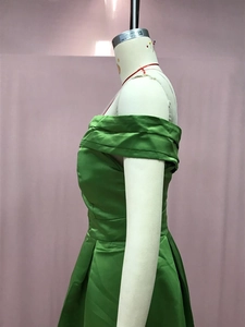 Détail d'une robe de soirée en satin vert avec fronces à la taille et fente latérale