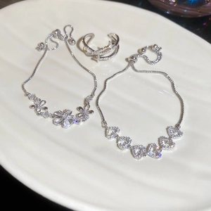Gros plan de bracelets fleurs en zircon et bagues cœurs sur une assiette décorative