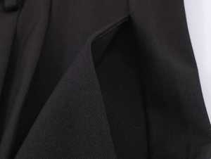 Close-up of black twill fabric texture and side pocket detail on wide-leg trousers