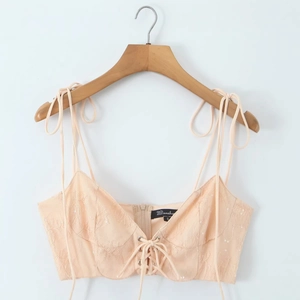 Sleeveless pink lace camisole with embroidery, sequins and front tie detail on a hanger