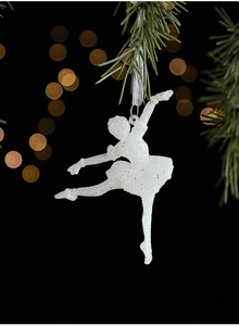 Close-up of a white glittery ballerina ornament hanging on a pine branch with bokeh lights