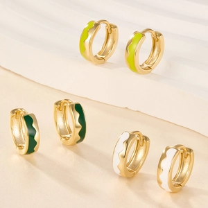 Detail of colorful enamel hoop earrings in green and white on minimalist stone steps