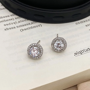 Macro detail of silver halo stud earrings with round cubic zirconia and pavé stones