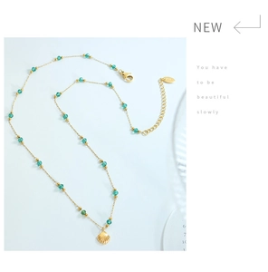 Close-up of 18K gold plated necklace featuring green crystal beads and a shell pendant
