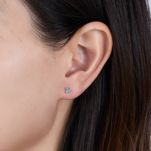 Detailed close-up of a triple turquoise stud earring set in gold on a model's ear