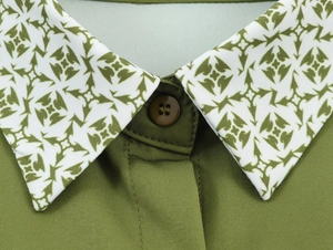 Close-up of elegant shirt collar featuring green geometric prints and a resin button detail