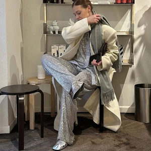 Fashionable women's suit with silver sequin shirt and shorts under a white coat
