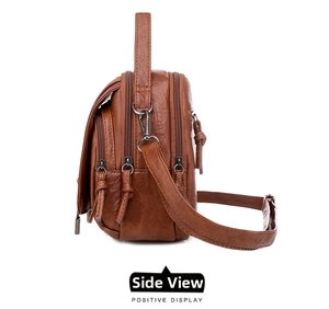 Detail of a vintage brown leather crossbody bag with multiple zipper layers and bronze hardware